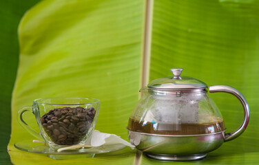 Coffee beans in a glass cup on a banana leaf background