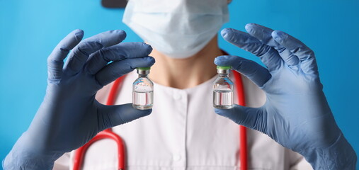 Close-up of scientist holding two bottles with injection in blue gloves. Dose of chemical substance in laboratory. Vaccination, analysis, test, lab concept