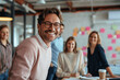 © btiger - Smiling professional man with glasses in pink sweater at table during team project in office