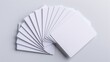 © konlawat - Multiple blank white credit cards arranged in a fan shape, casting subtle shadows on a pure white background, with sharp edges and glossy surfaces