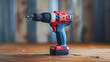 © Kowit - A red and blue power drill sits on a wooden table