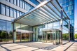 © Adisorn - Contemporary architectural design features sleek glass and steel entrance of a modern building with geometric lines, minimalist aesthetics, and a bright sunny day ambiance.
