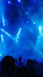 © Ilia - Crowd of people and enthusiastic fans in front of stage at concert, with bright lights and smoke from a smoke machine creating a vibrant atmosphere. Energy and excitement of a live music performance.
