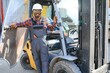 © Serhii - Portrait of a happy African American male worker driving forklift at workplace