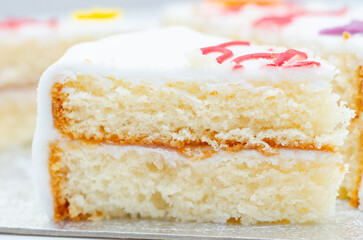 A slice of white cake with color frosting on top