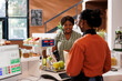 © DC Studio - Smiling black lady receiving assistance from African American vendor at the checkout counter with her locally grown produce. Customer at cashier desk in zero waster store purchasing organic products.