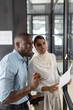 © Wavebreak Media - Discussing project, business colleagues using whiteboard and holding documents in office