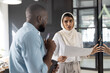 © Wavebreak Media - Discussing project details, colleagues holding documents and pen in modern office
