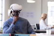 © Wavebreak Media - Using VR headset, businessman sitting at desk in modern office environment
