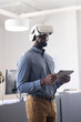 © Wavebreak Media - Using VR headset, businessman holding tablet and exploring virtual reality in office