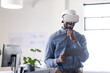 © Wavebreak Media - Using VR headset, man holding tablet and smiling in modern office setting, copy space