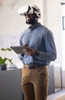 © Wavebreak Media - Using VR headset, businessman holding tablet and smiling in modern office