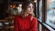 © NiK0StudeO - A woman in a red sweater is sitting in a cafe looking out the window