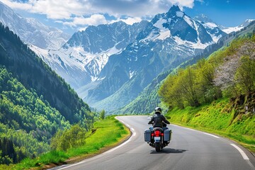 Poster - motorcyclist riding along the winding mountain road, surrounded by lush greenery and majestic mountains in springtime.