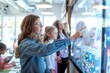 © Elmira - A young female teacher leads a classroom discussion, pointing to a digital display showing a colorful graphic. Students listen intently as she interacts with the touchscreen technology