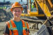© Elmira - A young man in a hard hat and safety vest smiles at the camera while standing in front of a large excavator at a construction site