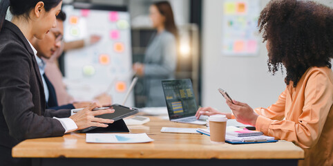 Wall Mural - Diverse business team analyzing data and discussing strategies during an office meeting, using documents and a laptop.