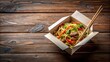© Sujid - Noodles with pork and vegetables in take-out box on wooden table, Asian cuisine, take-out, food delivery, stir-fry