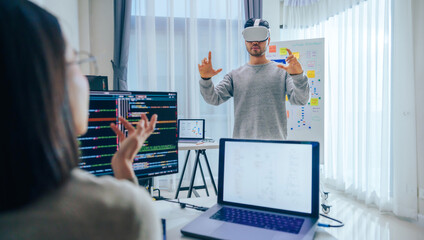 Wall Mural - asian software developer wearing a virtual reality headset works on a vr project, with a colleague f
