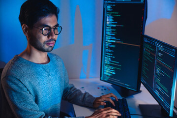 Wall Mural - indian software development working on coding computer screen and flowchart at night in modern offic