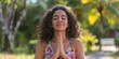 © Da - Peaceful and Happy Young Hispanic Woman Meditating with Hands Clasped, Eyes Closed, Practicing Yoga Breathing Exercises in Lush Tropical Park, Finding Inner Peace and Balance, High-Resolution Wallpape