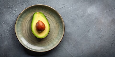 Poster - Ripe avocado sliced in half on a grey ceramic plate, avocado, fruit, healthy, green, vibrant, ripe, food, fresh