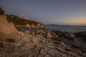 Hidden bay in sunrise. Looked at the small sand, pebble, beach in warm colors and the morning light. View of the sea at Xigia Sulfur Beaches, Ionian Islands, Greece