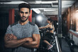 © peopleimages.com - Man, portrait and confident in gym for exercise, bodybuilding and personal training for health or muscle strength. Male person, arms crossed and proud for active living, fitness and cardio workout.