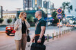 © qunica.com - Two business professionals discussing while standing on a busy city street at night, with blurred lights and traffic in the background.