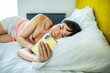 © Marko Geber - Smiling Asian woman using smartphone at home