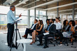 © peopleimages.com - Businessman, coach and presentation with team in seminar for meeting, conference or speech at office. Man, speaker or mentor talking, training staff or audience in workshop or convention at workplace