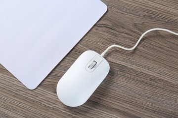 Poster - Computer mouse with mousepad on wooden desk, top view