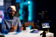 © DC Studio - Focus on professional video production tech used for capturing footage on content creator filming various sketches for his internet channel. Vlogging camera and media star in blurry background talking