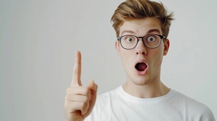Young man surprised  pointing at blank space  wearing glasses.