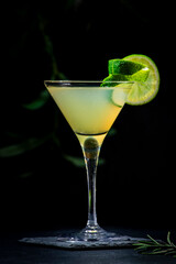 Wall Mural - Classic alcoholic cocktail with vodka, syrup, lime, juice and ice in martini glass, dark background