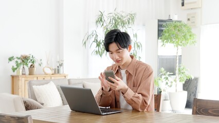パソコンとスマートフォンを使う男性