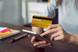 © Chayjitti - Woman hand holding a credit card and using smartphone to pay online. The concept of online shopping and payment.