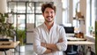 © Nia™ - Portrait of young smiling man looking at camera with crossed arms. Happy man standing in creative office. Successful businessman standing in office with copy space - generative ai