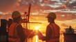 © Copi - Two engineers in hard hats and safety vests are looking at the sunset over a busy shipping port. They are discussing the logistics of a new project.