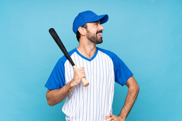 Young man playing baseball over isolated blue background happy and smiling