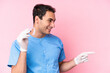 © luismolinero - Dentist caucasian man holding invisible braces isolated on pink background pointing finger to the side and presenting a product