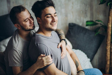 Wall Mural - Two sexy blue guys enjoying being together, hugging each other tenderly lying on bed in underwear. Men having happy and cheerful expression. Alternative same-sex Love and Tenderness Concept