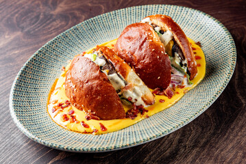 Wall Mural - Two stuffed buns with creamy sauce, garnished with herbs, served on a blue plate