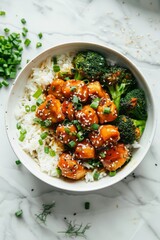 Wall Mural - Overhead photo saucy korean chicken with rice and broccoli in a white bowl on a white marble background