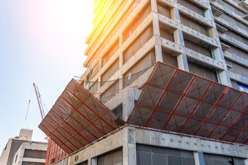 Wall Mural - Corner of the facade of the building under construction is covered with a protective construction net. Inscription Safety first. Low angle view.