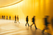 © Minimal Blue - Blurred motion of people walking in a modern, yellow-colored corridor, creating a dynamic and vibrant scene