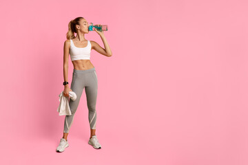 Wall Mural - Slim Young Lady Drinking Water Holding Towel Standing Over Yellow Background In Studio. Workout Break.