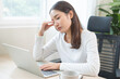 © KMPZZZ - Tired asian young woman burnout, stressed from problem work at desk in office, looking at laptop computer, feeling sick, pain eye strain rubbing dry irritated eyes fatigued working late on deadline.