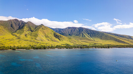 Wall Mural - aerial view of green volcanic and mountainous landscape meeting the bright blue coastline and shallo