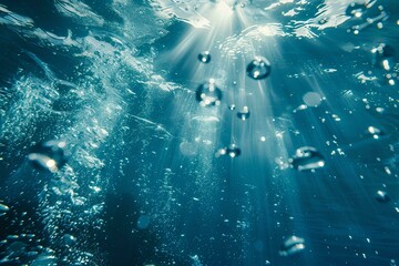 Abstract underwater background with sun rays shining through the water surface. Deep blue sea and white bubbles on dark ocean floor